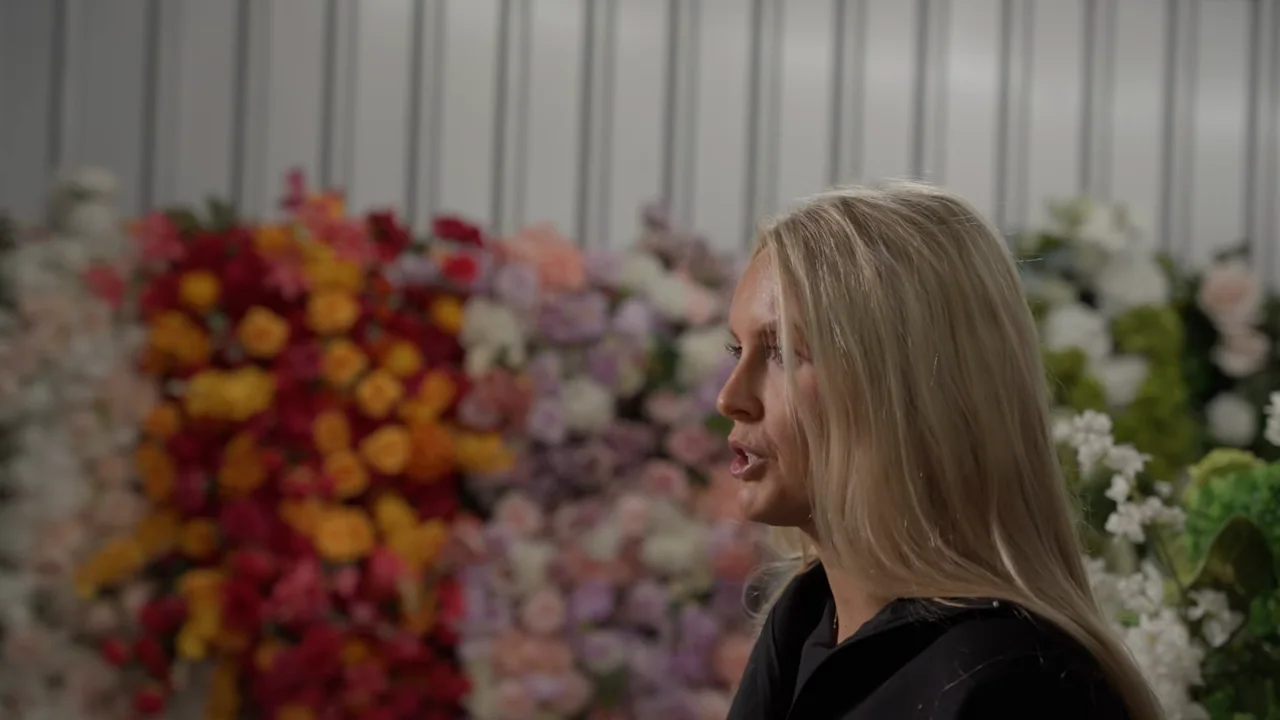 The seated interview returns with an insert of another person arranging flowers.