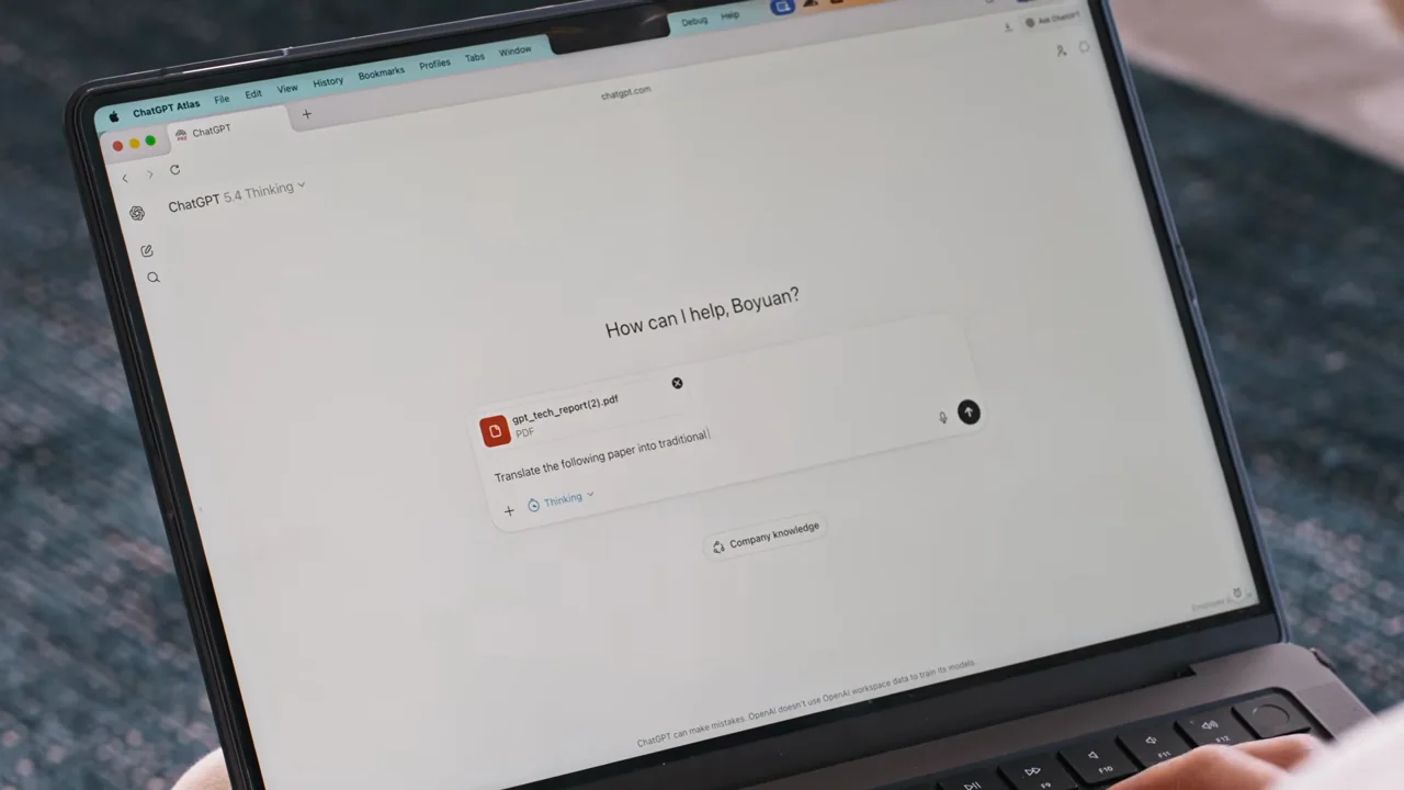 A laptop shows an attached document and a new prompt.