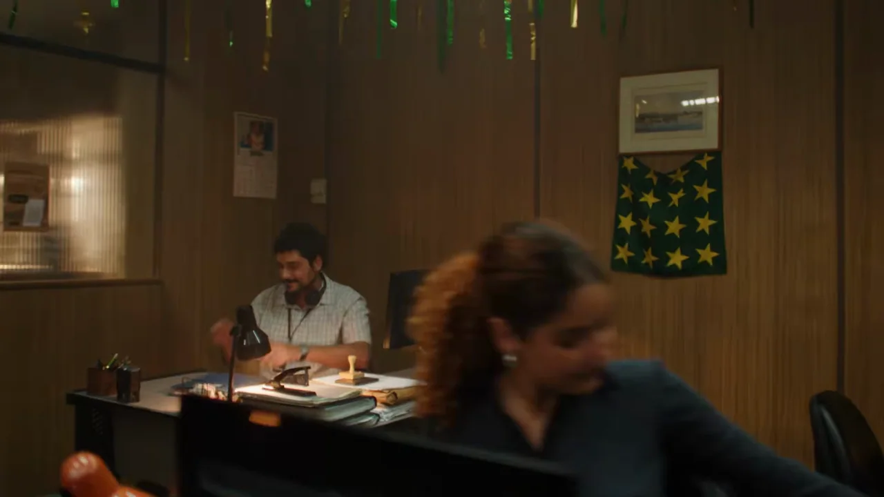 People move through a decorated office around a seated worker.