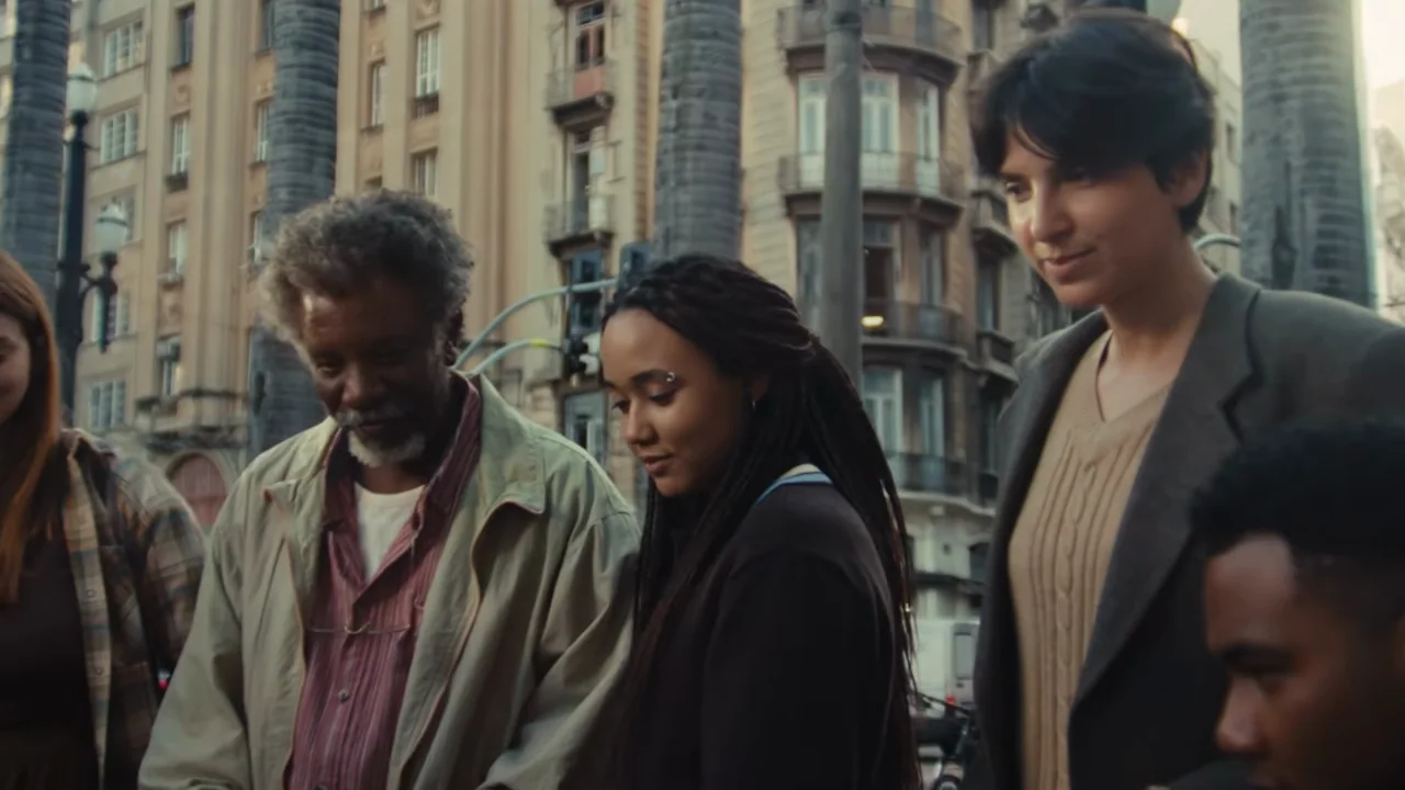 Close faces give way to more of the group around a street table.